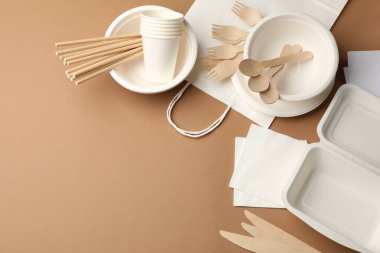 Kahverengi arka planda tek kullanımlık sofra takımı var. Metin için boşluk