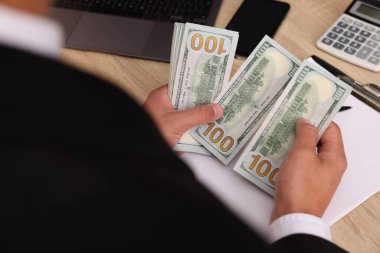 Ahşap masada dolar sayan adam, yakın plan.