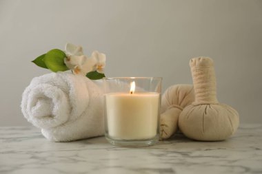 Beautiful spa composition with burning candle on white marble table, closeup
