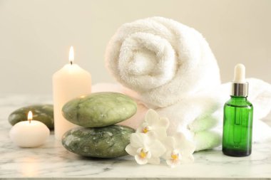 Beautiful spa composition with burning candles on white marble table, closeup