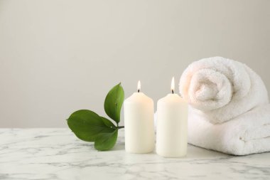 Yakıcı mumlar, havlular ve yapraklar beyaz mermer masada, yakın plan. Metin için boşluk