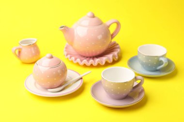 Beautiful ceramic tea set for children on yellow background, closeup