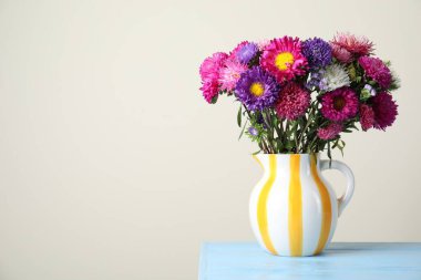 Vazodaki güzel çiçekler açık mavi ahşap masa üzerinde gri arka planda. Metin için boşluk