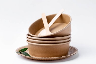 Beyaz arkaplanda tek kullanımlık eşyalar ve yeşil yapraklar, yakın plan