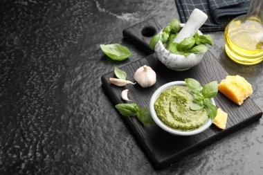 Taze pesto sosu ve siyah desenli masa üzerindeki malzemeler, metin için yer.