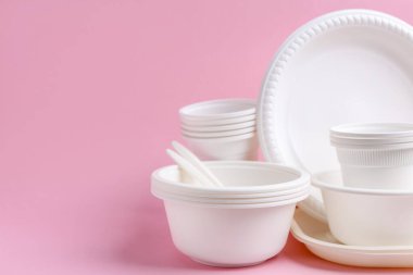 Pembe arka planda tek kullanımlık plastik sofra takımı, yakın plan. Metin için boşluk