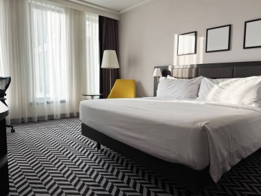 Büyük rahat bir yatak, şık bir otel odasında koltuk ve lambalar.