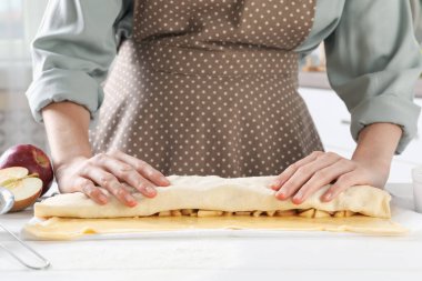 Mutfaktaki beyaz ahşap masada nefis elmalı turta yapan kadın.