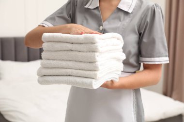 Otel odasında beyaz havlu yığını olan oda hizmetçisi, yakın plan.