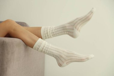 Çoraplı kadın evdeki beyaz duvarın yanındaki kanepede, yakın plan.