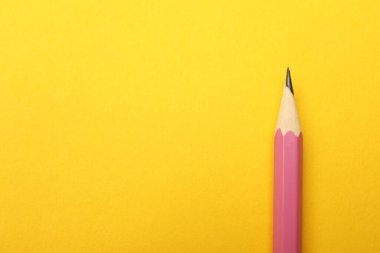 Sarı arka planda keskin bir grafit kalem, üst manzara. Metin için boşluk