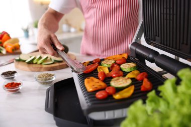 Mutfakta elektrikli ızgarada sebze pişiren adam, yakın plan.