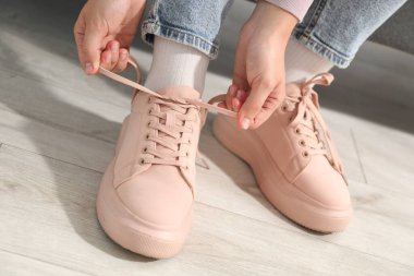 Bej ayakkabı bağcığını içeri bağlayan kadın, yakın plan.