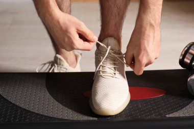 Ayakkabı bağcığını bağlayan adam içeride, yakın plan.