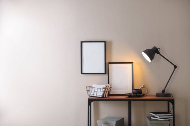 Şık lamba, diğer dekor ve kitaplar bej duvarın yanındaki konsol masasında, metin için boşluk