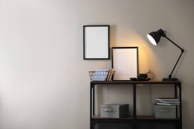 Şık lamba, diğer dekor ve kitaplar bej duvarın yanındaki konsol masasında, metin için boşluk