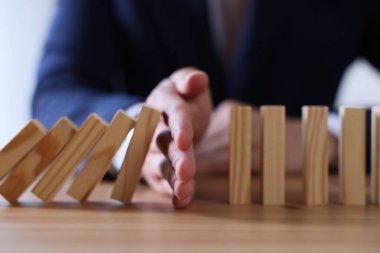 Risk. Tahta masada domino efektini durduran adam, yakın plan.