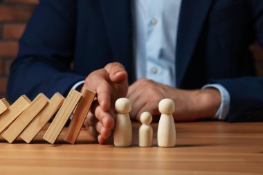 Risk. Tahta masada insan figürlerini domino etkisinden koruyan adam, yakın plan.