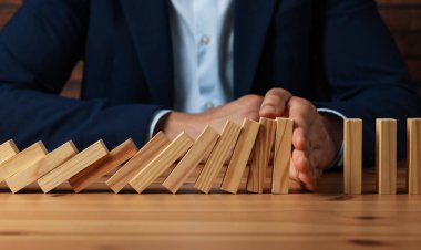 Risk. Tahta masada domino efektini durduran adam, yakın plan.