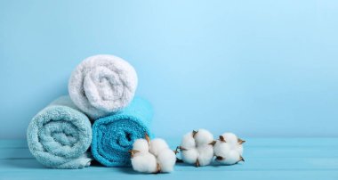 Temiz havlular ve açık mavi arka planda pamuk çiçekleri. Metin için boşluk