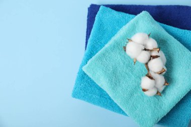 Temiz havlular ve açık mavi arka planda pamuk çiçekleri, üst manzara. Metin için boşluk
