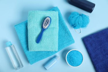 Temiz havlular ve açık mavi arka planda kişisel hijyen ürünleri.