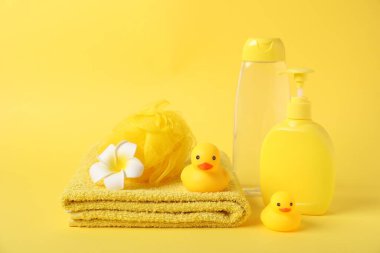 Taze havlu, kozmetik ürünler ve sarı arka planda plastik ördekler.