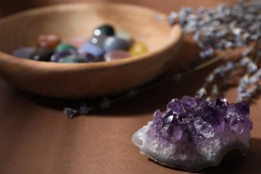 Kahverengi arka planda farklı güzel değerli taşlar ve lavanta çiçekleri, seçici odak