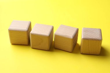 Sarı arkaplanda boş tahta küpler, yakın plan.