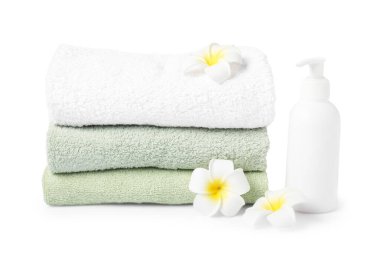 Taze havlu yığını, kozmetik ürünler ve beyaza izole edilmiş tesisat çiçekleri.
