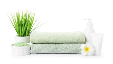 Taze havlu yığını, kozmetik ürünler ve beyaz üzerine izole edilmiş çiçek dekoru.