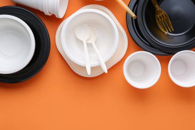 Turuncu arka planda tek kullanımlık plastik sofra takımı. Metin için boşluk
