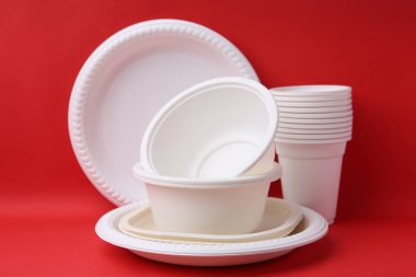 Kırmızı arkaplanda tek kullanımlık plastik sofra takımı, yakın plan