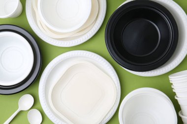 Açık yeşil zemin üzerinde tek kullanımlık plastik sofra takımı, düz yatıyordu