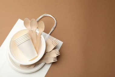 Kahverengi arka planda tek kullanımlık sofra takımı, üst görünümde. Metin için boşluk