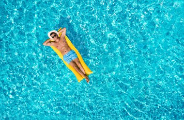 Happy man with inflatable mattress in swimming pool, top view. Summer vacation