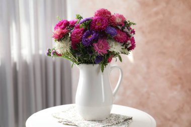 İçerideki beyaz masada vazodaki güzel çiçekler, yakın plan.