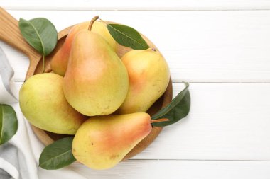 Taze armutlar ve beyaz ahşap masa üzerinde yeşil yapraklar. Metin için boşluk