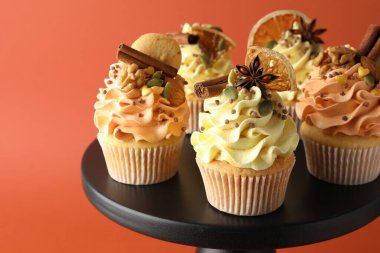 Dondurmalı, kurabiyeli, baharatlı ve portakal dilimli lezzetli kekler mercan arka planda duruyor, yakın plan. Sonbahar atmosferi