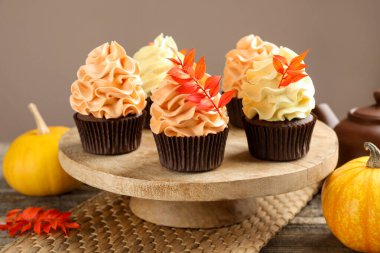 Gri arka planda, üzerinde kırmızı yapraklar olan lezzetli kapkekler, yakın plan. Sonbahar atmosferi