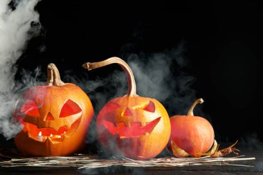 Cadılar Bayramı kutlaması. Ürkütücü balkabağı fenerleri ve siyah arka planda duman.