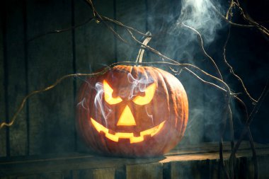 Cadılar Bayramı kutlaması. Ürkütücü balkabağı feneri ve dumanı ahşap arka planda