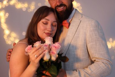 Evlilik teklifi yapıyor. Nişan yüzüklü kadın, çiçekler ve nişanlısı açık gri arka planda, bokeh etkisi.