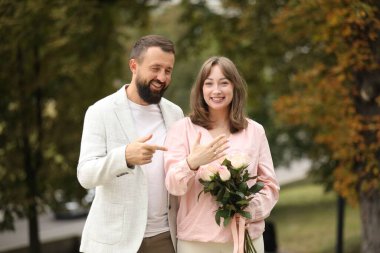 Evlilik teklifi yapıyor. Nişan yüzüklü kadın, çiçekler ve nişanlısı dışarıda.