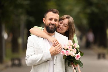 Evlilik teklifi yapıyor. Nişan yüzüğü, çiçekleri ve dışarıda mutlu nişanlısı olan bir kadın.