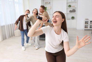 Genç bir kadın evde arkadaşlarıyla karaoke yapıyor, seçici odaklı.