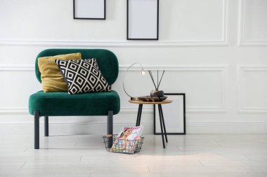 Şık lamba, sazlık dağıtıcı ve koltuk kenarında yastıklı dergi.