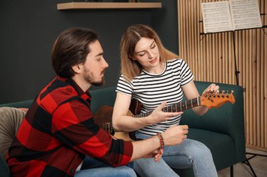 Evdeki kanepede gitar çalmayı öğreten öğretmen.