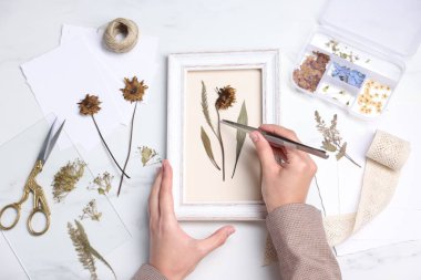 Beyaz mermer masa, üst manzara, resim çerçevesi içine kuru çiçekler koyan kadın