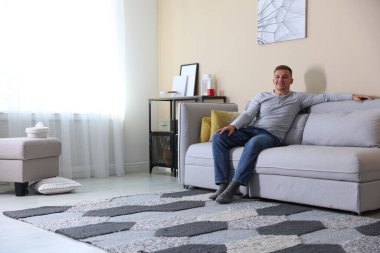 Mutlu genç adam evdeki kanepede dinleniyor, mesaj için yer var.